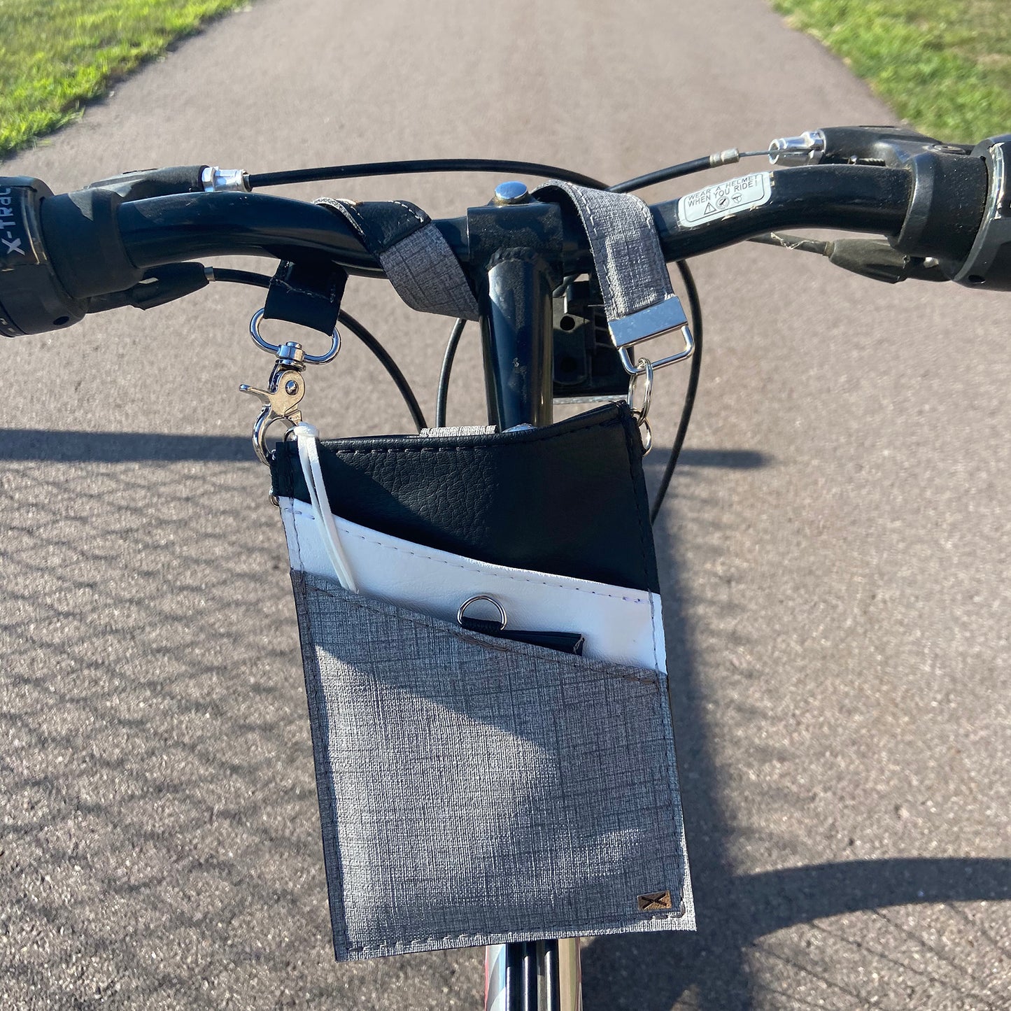 A black and gray vegan leather phone pouch with a black vegan leather magnetic wristlet key chain and a black and gray removable three pocket wallet used as a bike bag.