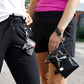 A person with a black vegan leather phone pouch with a black vegan leather magnetic wristlet key chain and a black removable three pocket wallet and black lip balm holder set. Another Person  with a black and gray vegan leather bracelet, keychain, three pocket wallet, and a black lip balm holder